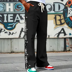 Detail view of men's hip hop black pants featuring paisley pattern and side snap buttons