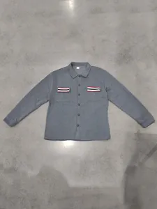 Detailweergave van een grijze fleece jas met gestreepte zakken en drukknopen
