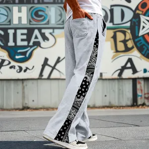 Close-up of men's grey hip-hop pants featuring paisley side panels and snap buttons