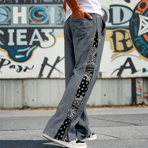 Detail shot of men's grey hip hop pants featuring paisley side panels and snap buttons.