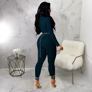 Rear view of a sexy dark teal long sleeve jumpsuit featuring pink ankle lace-up details