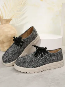 Detail van getextureerde grijze geweven veterschoenen voor dames met dikke beige zolen.