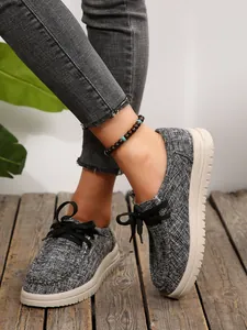 Detail van grijze getextureerde damesloafers met dikke witte zolen op hout