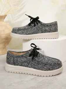 Zijwaarts detail van modieuze grijze getextureerde veterloafers met beige dikke zolen