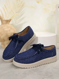 Detailopname van blauwe denim loafers met beige zolen en een stijlvolle vetersluiting