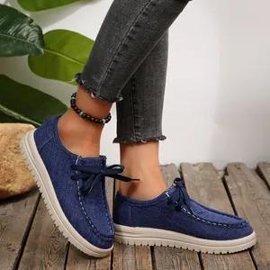 Close-up van stijlvolle blauwe denim instappers met een ronde neus en witte zool