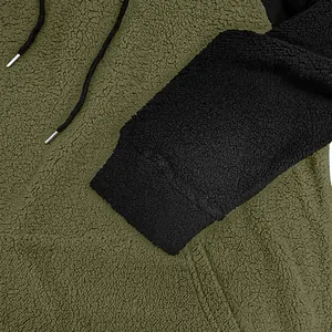 Nahaufnahme des weichen Sherpa-Fleece-Stoffs an einem grün-schwarzen Kapuzenpulli-Detail.