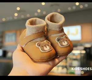 Close-up of brown soft-sole infant sock shoes with cute bear embroidery for winter warmth