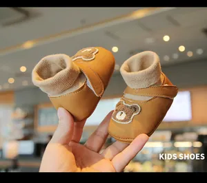Close-up detail of brown baby winter walking shoes with a cute bear patch and soft knit ankle