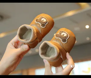 Close-up detail of brown baby winter walk shoes featuring cute plush bear embroidery