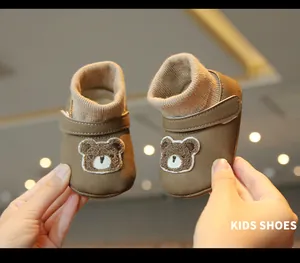 Close-up of brown winter baby sock shoes with cute plush bear embroidery.