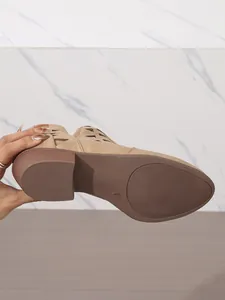 Vista dettagliata della suola e del design traforato di questi stivaletti beige con tacco.