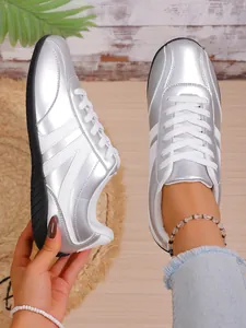 Detail of metallic silver sneakers for women with white lace-up and classic stripes