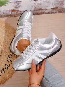 Close-up of silver and white casual sneakers showing metallic texture and white laces.
