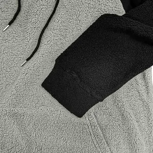 Nahaufnahme der dicken Sherpa-Fleece-Struktur und des Color-Block-Ärmels am Herren-Hoodie.