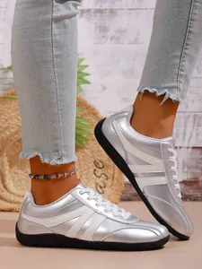 Close-up of silver metallic women's casual sneakers with white stripes and black soles