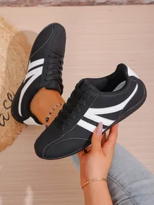 Close-up detail of black breathable women's sneakers with white stripes in lifestyle setting