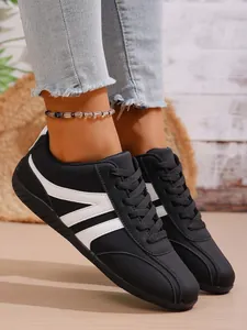 Fashionable black women's sneakers with white stripes worn with denim jeans for casual look.