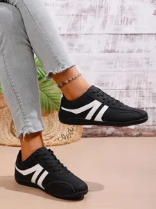Detail view of stylish women's black and white retro sneakers paired with denim jeans.