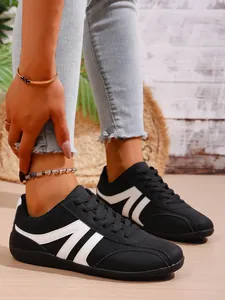 Detailed view of black breathable sneakers with white stripes and lace-up closure