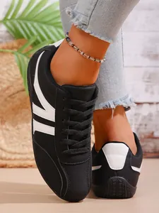 Detailed view of stylish black women's casual sneakers with white stripe accents on a model