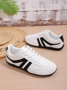 Close-up view of white women's sports sneakers featuring black side stripes and textured leather