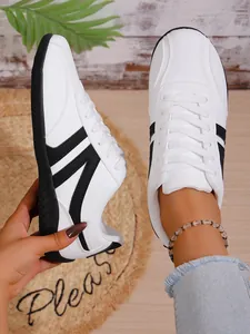 Detailed view of women's white casual sneakers with black stripes and lightweight sole