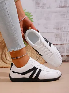 White women's casual sneakers with black stripe details shown in a lifestyle setting