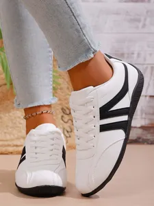 Detailed macro shot of women's white leather sneakers with black V-shaped accents.