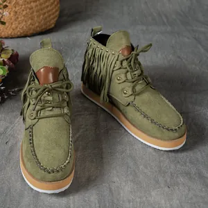 Detailed view of olive green suede fringe boots with metal rivets and thick soles.