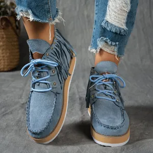 Detailed macro shot of women's western-style blue suede fringe boots with lace-up detail