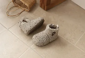 Detailed overhead view of cozy fleece girls' winter boots with horn buckles on tiled floor