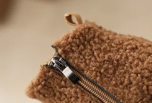 Close-up detail of the durable metal zipper on girls' warm fuzzy brown snow boots