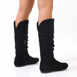 Close-up of black suede-like tall flat boots with slouchy texture and stylish V-cut cuff design