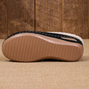 Macro view of the non-slip brown sole and warm faux fur lining on a black wedge slipper