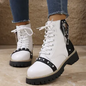 Gros plan de bottines à plateforme cloutées noir et blanc avec tête de mort et chaînes.