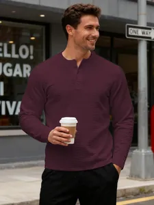 Close-up of men's burgundy waffle knit long sleeve Henley sweatshirt in urban setting.