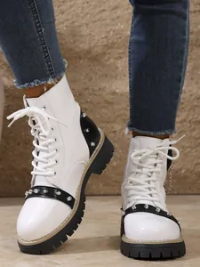 Gros plan de bottines à plateforme blanches avec clous argentés et accents noirs