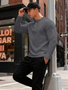Close-up of men's grey waffle knit Henley shirt with button placket and textured fabric.