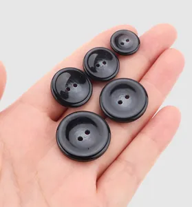 Detail view of five black resin buttons in various sizes held in a palm for scale.