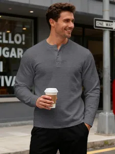 Detailed view of grey textured long-sleeve Henley shirt worn in urban setting