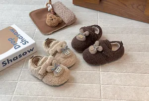 Pantofole a coniglietto marroni e beige per bambine presentate su un pavimento strutturato