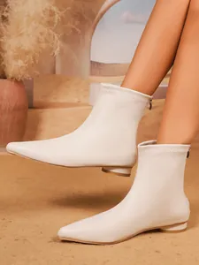 Detailansicht eleganter weißer Stiefeletten mit spitzer Kappe und Elastikeinsatz.
