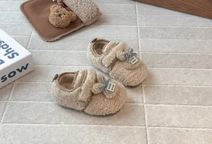 Primo piano di graziose scarpe in peluche beige per neonati con orecchie di coniglio e fiocchi.