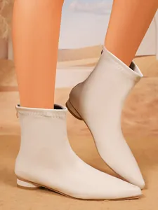 Detailaufnahme von modischen, cremeweißen elastischen Stiefeletten mit spitzer Zehenpartie