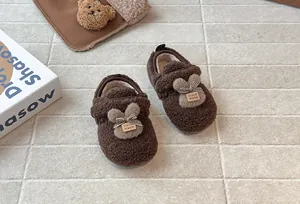 Dettaglio di graziose scarpe in peluche marroni per bambini con orecchie di coniglio e fodera calda