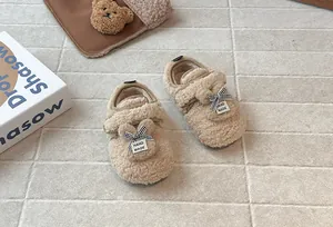 Dettaglio di scarpine in pile beige per neonata con orecchie di coniglio in peluche e fiocchi.