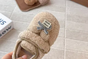 Vista dettagliata scarpe in peluche bambina con fiocco a scacchi e etichetta fatta a mano