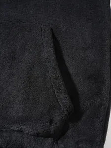 Macro close-up showing the soft black fleece fabric and pocket stitching detail on a hoodie.