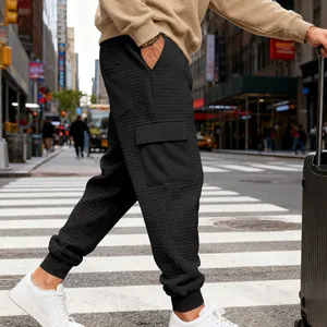 Dettaglio dei pantaloni cargo jacquard pesanti da uomo con grandi tasche laterali in città.